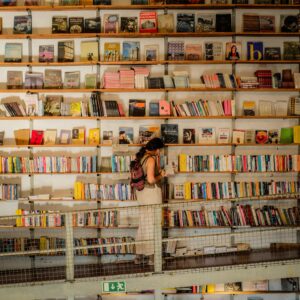 Warm and inviting bookshop in Lisbon, Portugal with a woman browsing books on wooden shelves.